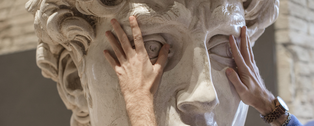 mani che toccano il volto del David di Michelangelo