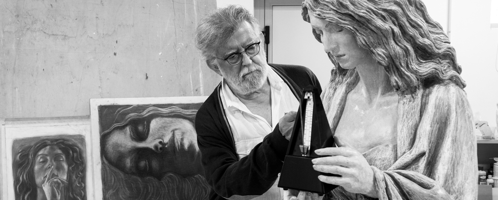 Foto in bianco e nero di Paolo Annibali nel suo studio osserva una delle sue opere in argilla