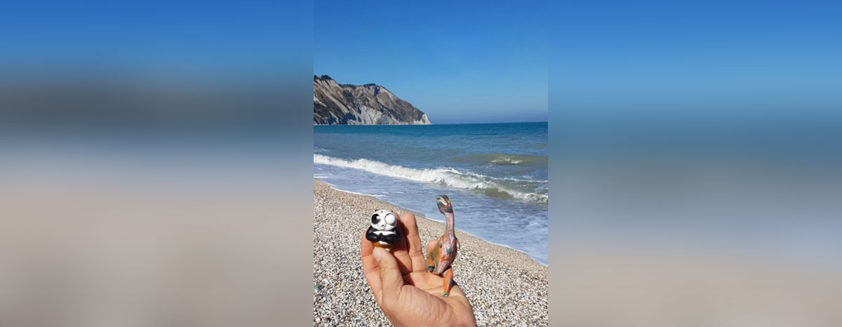 mano di bambino che tiene tra le dita dei giochi di plastica ritrovati in spiaggia